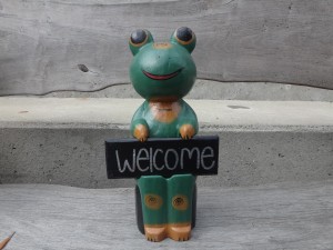 welcomeプレートを持った木彫りのカエル